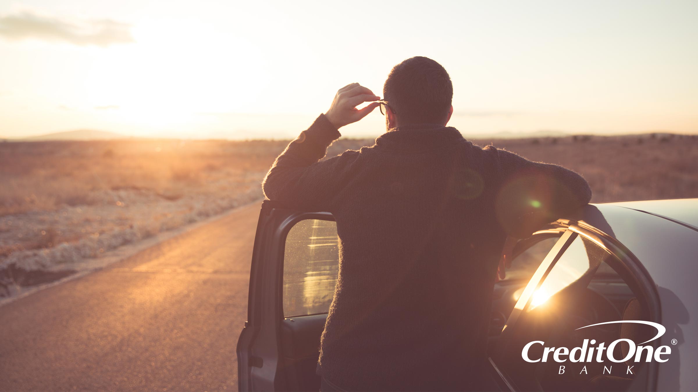 Man standing outside of his car staring to see what is beyond the horizon